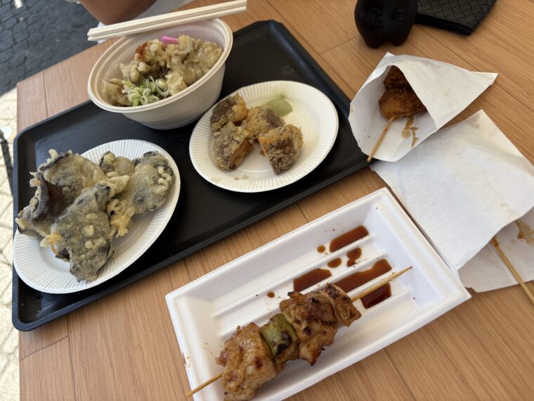 テーブルに並べられたしいたけ天ぷら、そば、串焼き、揚げ物などの料理