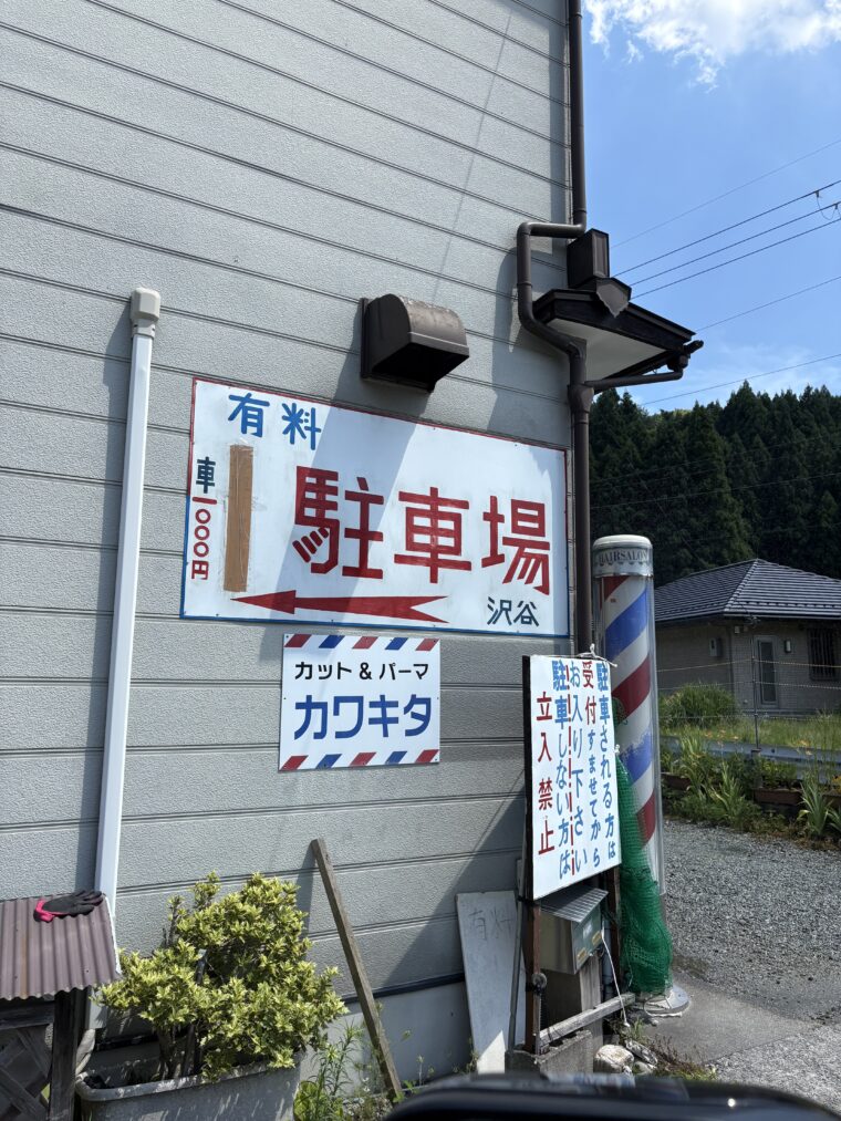 天川村の有料駐車場の看板と理容カワキタの外観
