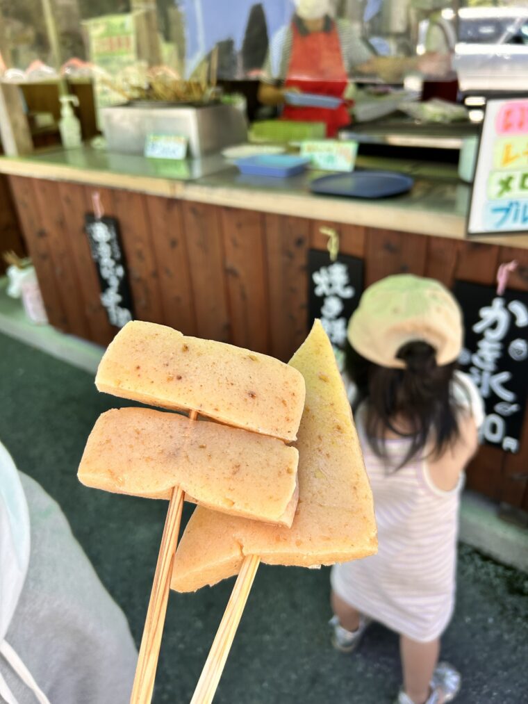 道の駅「吉野路黒滝」の屋台前で、甘辛い醤油だしが染みた名物・串こんにゃくを手に持っている様子。
