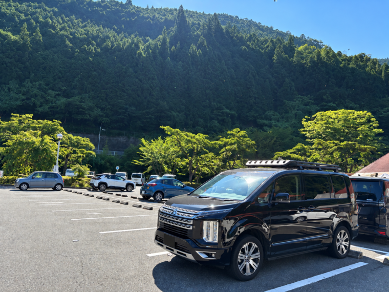 山あいの駐車場に停めたルーフキャリア付きの黒い三菱デリカD:5